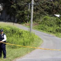 A police officer stands near a house in Tateyama, Chiba Prefecture, where the body of a young girl was found on Tuesday. | KYODO