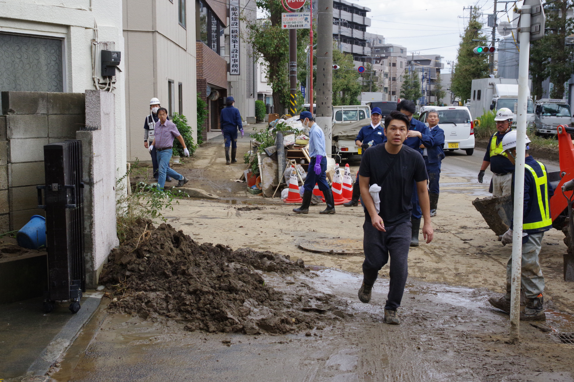 Workers struggle to clean mud and garbage left after the flood in the Kami-Maruko district near JR Musashikosugi Station in Kawasaki, Kanagawa Prefecture, on Tuesday. The flood is believed to have been caused by back-streaming from underground drains connected to the Tama River due to Typhoon Hagibis. | REIJI YOSHIDA