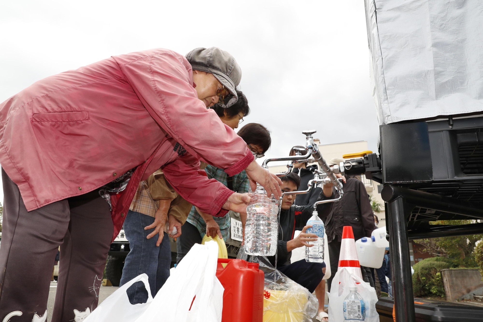 People in the town of Marumori, Miyagi Prefecture, collect water supplies on Tuesday after the entire neighborhood was flooded and homes had their water cut off following Typhoon Hagibis. | KYODO