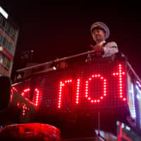 What a riot: A police officer stands atop a platform outside Shibuya Station and directs Halloween revelers at Shibuya crossing on Oct. 26. | JULIA BERGIN