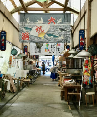 Spruced up: The interior of the Kure Taisho Town Market's wooden roof is decorated with colorful fishermen's banners. | ROBBIE SWINNERTON