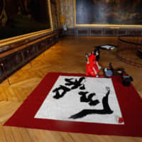 Artist Yukako Matsui writes the name of Japan\'s Reiwa Era at the Palace of Versailles on Oct. 21 in honor of Emperor Naruhito\'s enthronement. Japan has been spared the forces of populism that have shaken Western countries. | AFP-JIJI