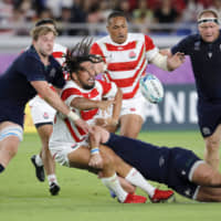 Japan\'s Shota Horie passes the ball as he is tackled during Sunday night\'s match. | AP