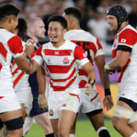 Japan\'s Kenki Fukuoka (center) is congratulated by teammate Kazuki Himeno after scoring his second try on Sunday. | AP
