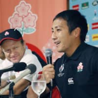 Japan scrumhalf Yutaka Nagare speaks at a news conference on Saturday as assistant coach Tony Brown looks on. The Brave Blossoms face South Africa in the Rugby World Cup quarterfinals on Sunday. | KYODO