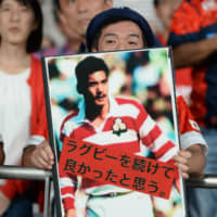 A fan at Tokyo Stadium holds up a photo of Seiji \"Mr. Rugby\" Hirao, the former player and coach who died three years ago Sunday and is credited with popularizing Japanese rugby in the 1990s. | DAN ORLOWITZ