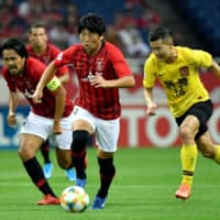 Reds\' Yuki Muto dribbles the ball in front of teammate Shinzo Koroki (left) and Guangzhou midfielder Huang Bowen on Wednesday night at Saitama Stadium. | AFP-JIJI