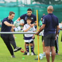 Former England flyhalf Jonny Wilkinson demonstrates kicking technique, while ex-South African winger Bryan Habana (center) looks on at Monday\'s \"Rugby Introduction Days\" event in Tokyo. | KAZ NAGATSUKA