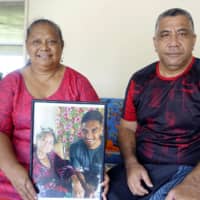 Mariana (left) and Faalogo Kapeli Lafaele hold up a picture of their son, Japan international Timothy Lafaele, at their home in Apia. | KYODO