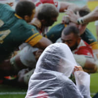 A woman walks past a Rugby World Cup billboard in the Shinagawa district of Tokyo on Saturday amid Typhoon Hagibis. | REUTERS