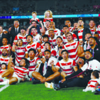 The Brave Blossoms pose for a group photo at Tokyo Stadium after their Rugby World Cup quarterfinal loss to South Africa on Sunday. | REUTERS