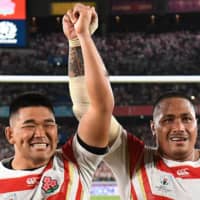 Japan props Koo Ji-won (left) and Asaeli Ai Valu celebrate after the team\'s Rugby World Cup Pool A win over Scotland in Yokohama on Sunday. | AFP-JIJI