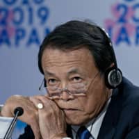 Deputy Prime Minister and Finance Minister Taro Aso listens to a question during a Group of 20 news conference on the sidelines of the annual meetings of the International Monetary Fund and World Bank Group in Washington on Oct. 18. | BLOOMBERG