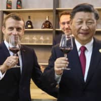 French President Emmanuel Macron and Chinese President Xi Jinping taste wine as they visit the French pavilion at the China International Import Expo in Shanghai on Tuesday. Xi reportedly is considering the possibility of visiting the United States soon. | AFP-JIJI