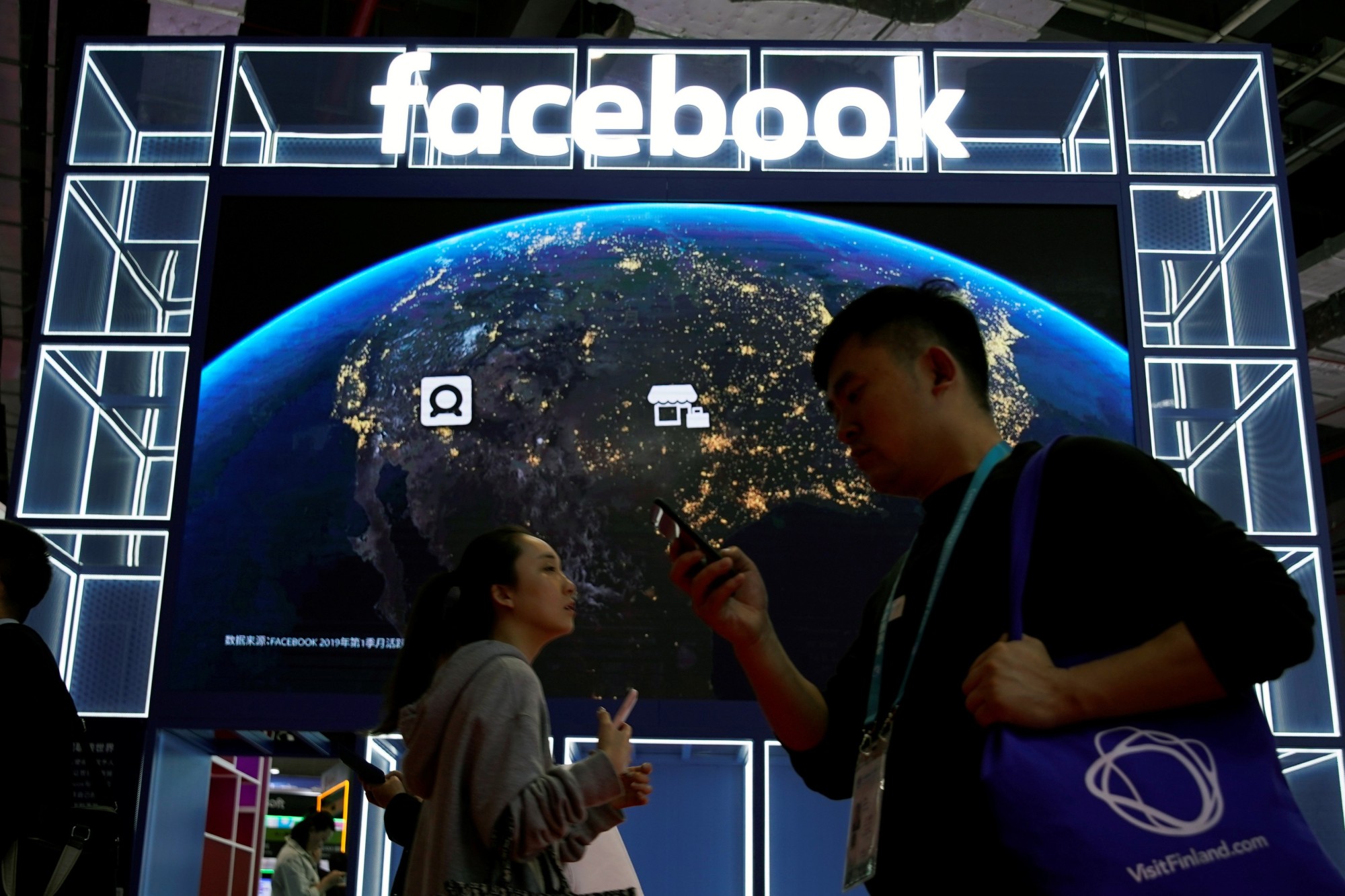 People walk by a Facebook sign at the second China International Import Expo in Shanghai on Wednesday. | REUTERS