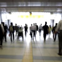 Morning commuters make their way to work in Tokyo on July 9. JR East is planning to introduce \'walk-through\' ticket gates that communicate with a specialized apps on passengers\' smartphones. | BLOOMBERG