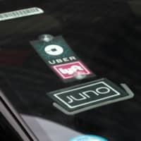 The Uber, Lyft and Juno logos are seen on a car as it drive up 6th Avenue in New York City last year. | REUTERS