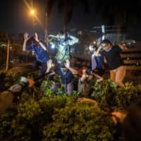 Police detain protesters and students after they tried to flee outside the Hong Kong Polytechnic University campus in the Hung Hom district of Hong Kong on Tuesday. A dwindling number of exhausted pro-democracy protesters barricaded inside the Hong Kong university defied warnings to surrender, as a police siege of the campus stretched through a third day and China sent fresh signals that its patience with nearly six months of unrest was running out. | AFP-JIJI