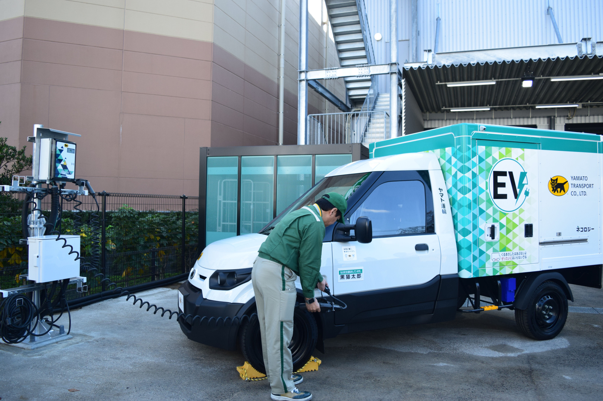 A Yamato Transport Co. driver charges a new electric truck Tuesday in Tokyo. The 2.85-ton vehicle is designed to be more driver-friendly in order to attract more workers amid the acute labor shortage in the transport industry. | MASUMI KOIZUMI