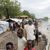 South Sudanese stand next to makeshift structures in the town of Pibor on Wednesday after heavy rains and floods forced hundreds of thousands of people to leave their homes. | REUTERS