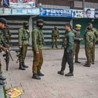 Security personnel stand near the site of a grenade blast at a market outside the campus of Kashmir\'s main university in Srinagar on Tuesday. | AFP-JIJI