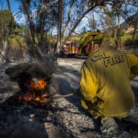 A firefighter controls a hotspot of the Maria Fire, in Santa Paula, Ventura County, California, Saturday. | AFP-JIJI