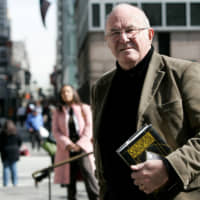 Author Clive James poses with a copy of his new book of essays \"Cultural Amnesia\" in New York\'s Bryant Park in 2007. | REUTERS