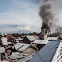Smoke rises after a small aircraft carrying about 17 passengers crashed in a densely populated area of Goma, in the Democratic Republic of Congo, on Sunday. | AFP-JIJI