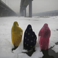 Hindu devotees perform rituals in the Yamuna River, covered by chemical foam caused by industrial and domestic pollution, during the Chhath Puja festival in New Delhi on Saturday. | AP