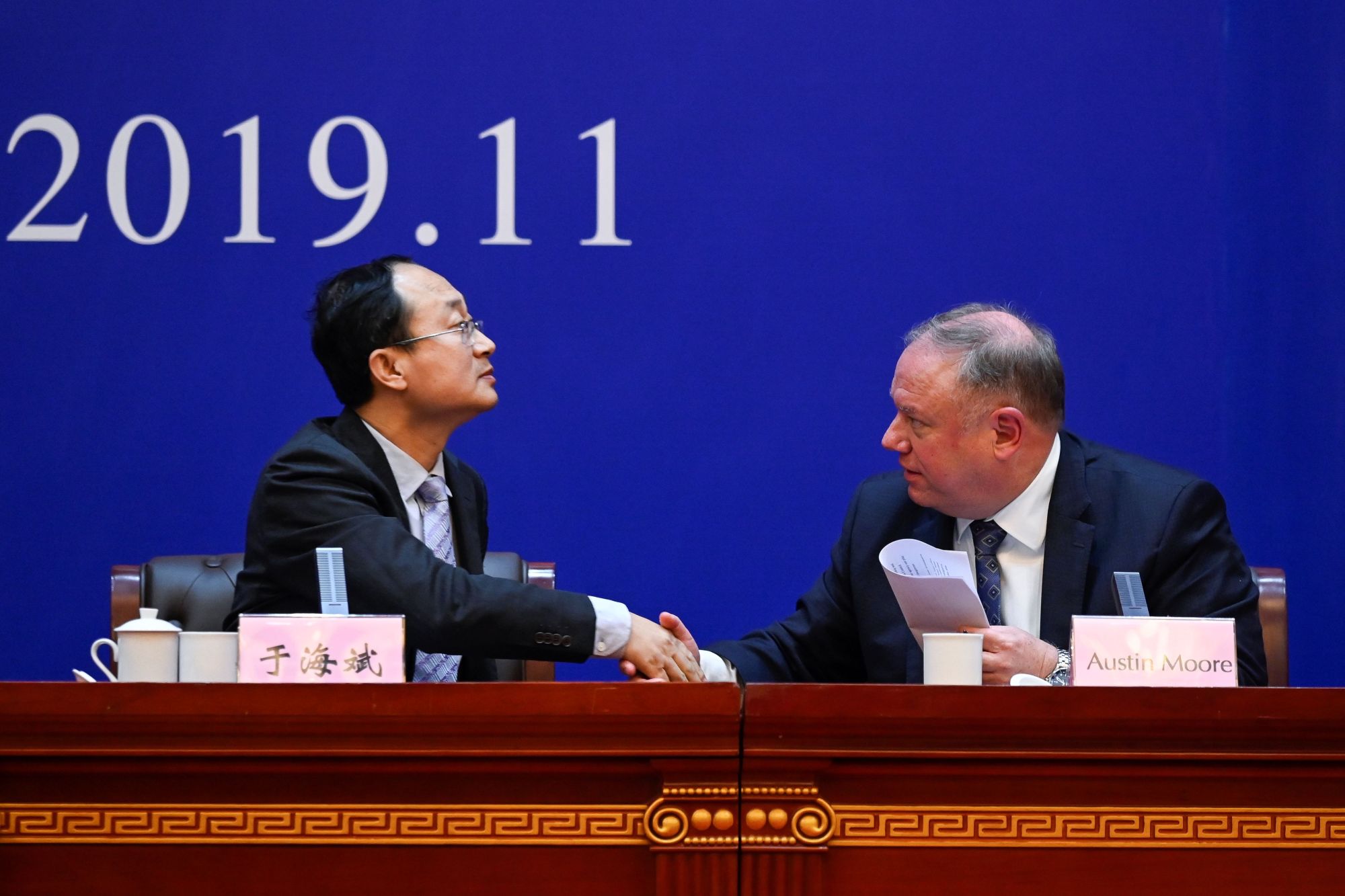 Yu Haibin, deputy director of China National Narcotics Control Commission, shakes hands with Austin Moore, an attache for the U.S. Department of Homeland Security and Immigration and Customs Enforcement, during a briefing in Xingtai, China, on Thursday. | AFP-JIJI