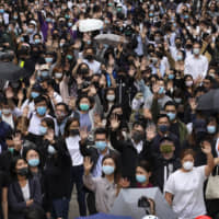 Office workers and pro-democracy protesters hold up their hands to represent their five demands as protests continue in Hong Kong on Tuesday. | AP