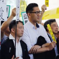 Democratic Party member and lawmaker Lam Cheuk-ting holds a placard that reads \"People\'s Hero\" as he supports nine pro-democracy activists outside a court in April. | BLOOMBERG