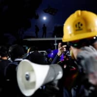Anti-government protesters react during a standoff with riot police at the Chinese University of Hong Kong in Hong Kong Tuesday. | REUTERS