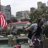 A protester holds an American flag at Hong Kong Polytechnic University on Wednesday. | AP
