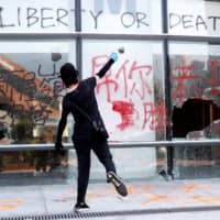 A protester throws a stone into a building at Hong Kong Polytechnic University on Nov. 11. | REUTERS