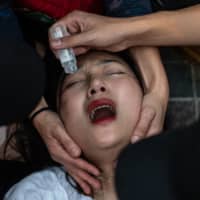 Medical volunteers help wash spray paint from a woman\'s eye as people attend a singing rally in Tsim Sha Tsui district in Hong Kong on Saturday. | AFP-JIJI