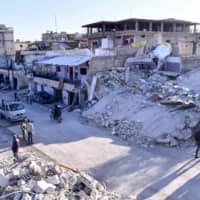 People inspecting damaged buildings following a reported Israeli airstrike on the Syrian village of Beit Saber, southwest of Damascus, Wednesday. The Israeli army confirmed that it carried out strikes against military sites in Damascus, in response to rocket fire from Syria the previous day. | SANA / VIA AFP-JIJI
