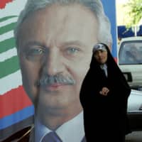 A woman walks past an election campaign poster of then economy and trade minister Mohammed Safadi in the northern Lebanese city of Tripoli im 2009. According to senior officials speaking on condition of anonymity and Lebanese press reports, key political players agreed that Safadi should be tasked with forming the next government. | AFP-JIJI