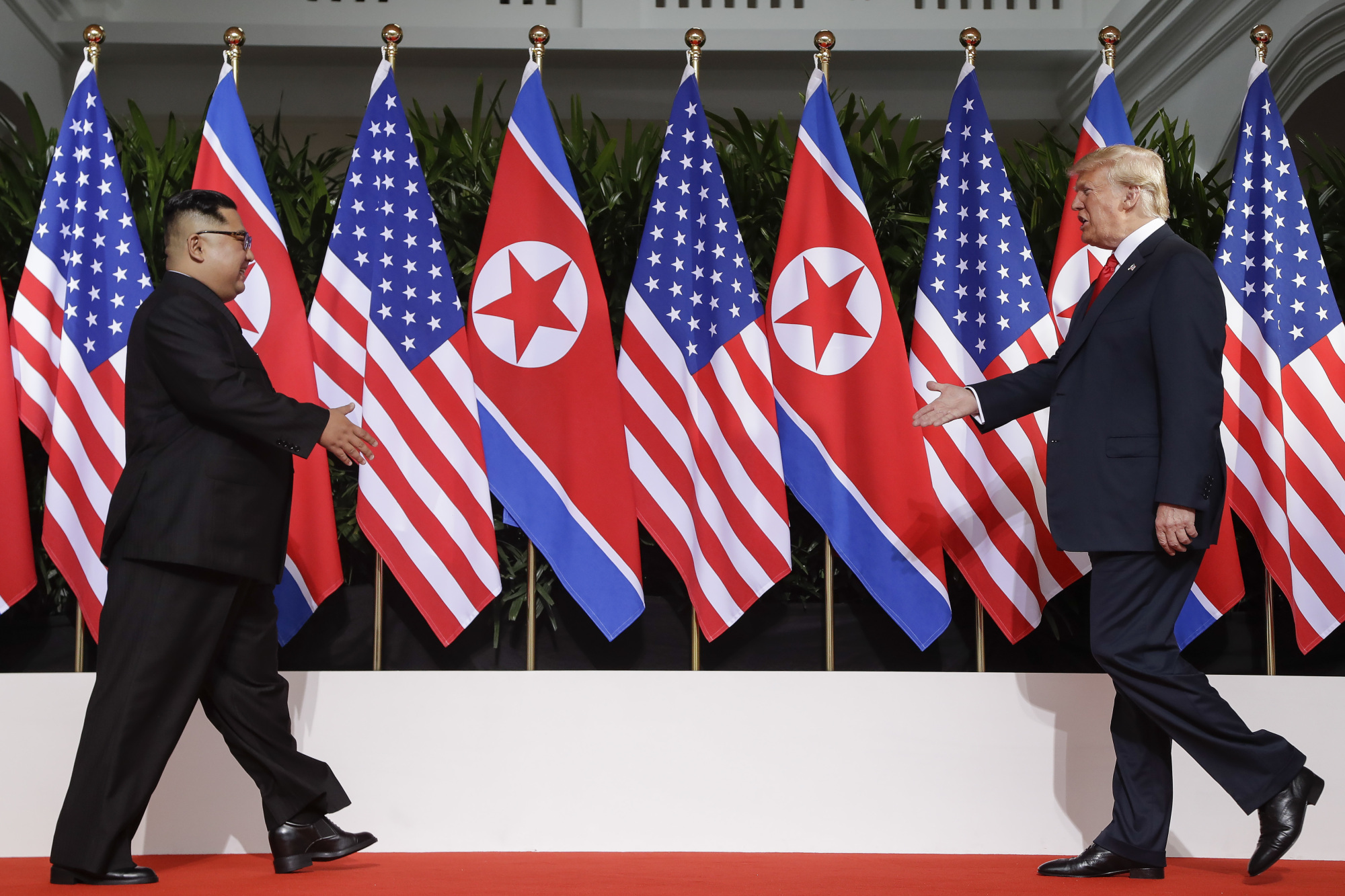 U.S. President Donald Trump and North Korea leader Kim Jong Un walk toward each other at the Capella resort on Sentosa Island in Singapore on June 12, 2018. | AP