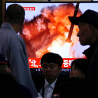 People watch a TV broadcast in Seoul on Oct. 31 showing file footage of a news report about North Korea firing two projectiles, possibly missiles, into the Sea of Japan. | REUTERS
