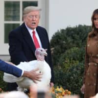 U.S. President Donald Trump pardons one of the 72nd National Thanksgiving Turkeys as Wellie Jackson, who raised the turkey, holds onto it and first lady Melania Trump looks on during ceremonies in the Rose Garden at the White House in Washington Tuesday. | REUTERS