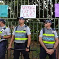 Members of the security forces stand guard outside the Venezuelan Embassy in Brasilia Wednesday. The placards read \"Latin America free,\" \"Women against fascism\" and \"Jail for the militiamen.\" | REUTERS