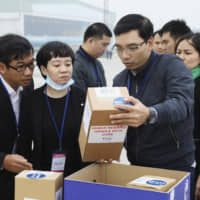 Vietnamese officials examine a box with human remains at the Noi Bai airport in Hanoi on Saturday. | VNA / VIA AP