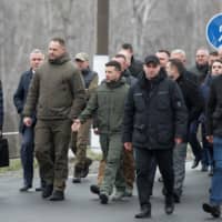 Ukrainian President Volodymyr Zelenskiy (center) visits a section of a restored bridge that was exploded during a military conflict between Ukrainian government forces and Russian-backed rebels, in the settlement of Stanytsia Luhanska, Ukrain, Wednesday. | REUTERS