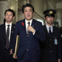 Prime Minister Shinzo Abe adjusts his tie as he arrives at the Lower House for an extraordinary Diet session on Oct. 4. | BLOOMBERG