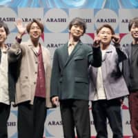 Members of the popular boy band Arashi wave during a news conference Sunday when it was announced the group will hold two concerts at the new National Stadium in May ahead of the 2020 Tokyo Olympics and Paralympics. | KYODO