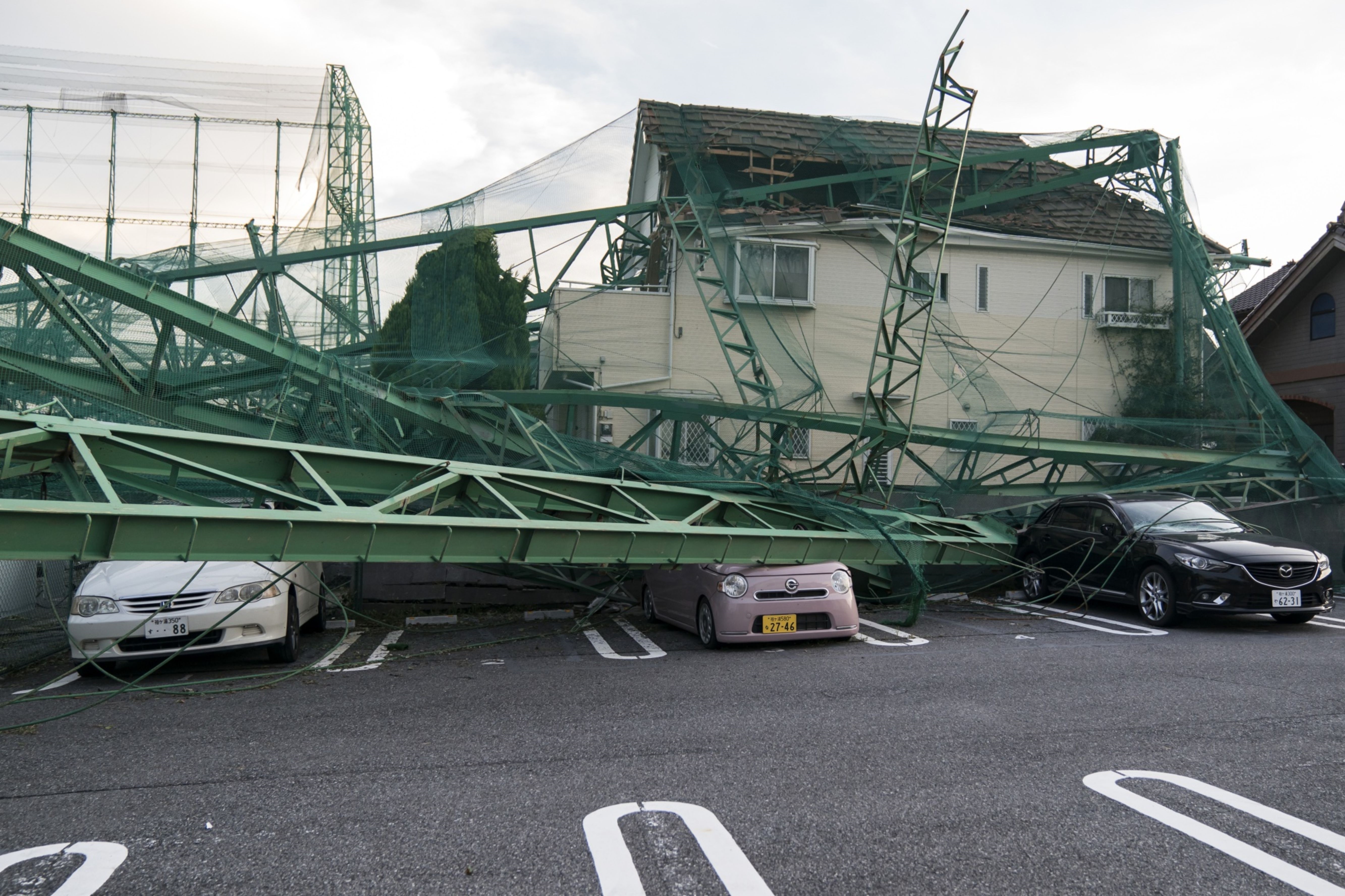 A fence around a driving range that collapsed on a house and cars due to Typhoon Faxai is seen on Sept. 9 in Ichihara, Chiba Prefecture. | GETTY IMAGES / VIA BLOOMBERG