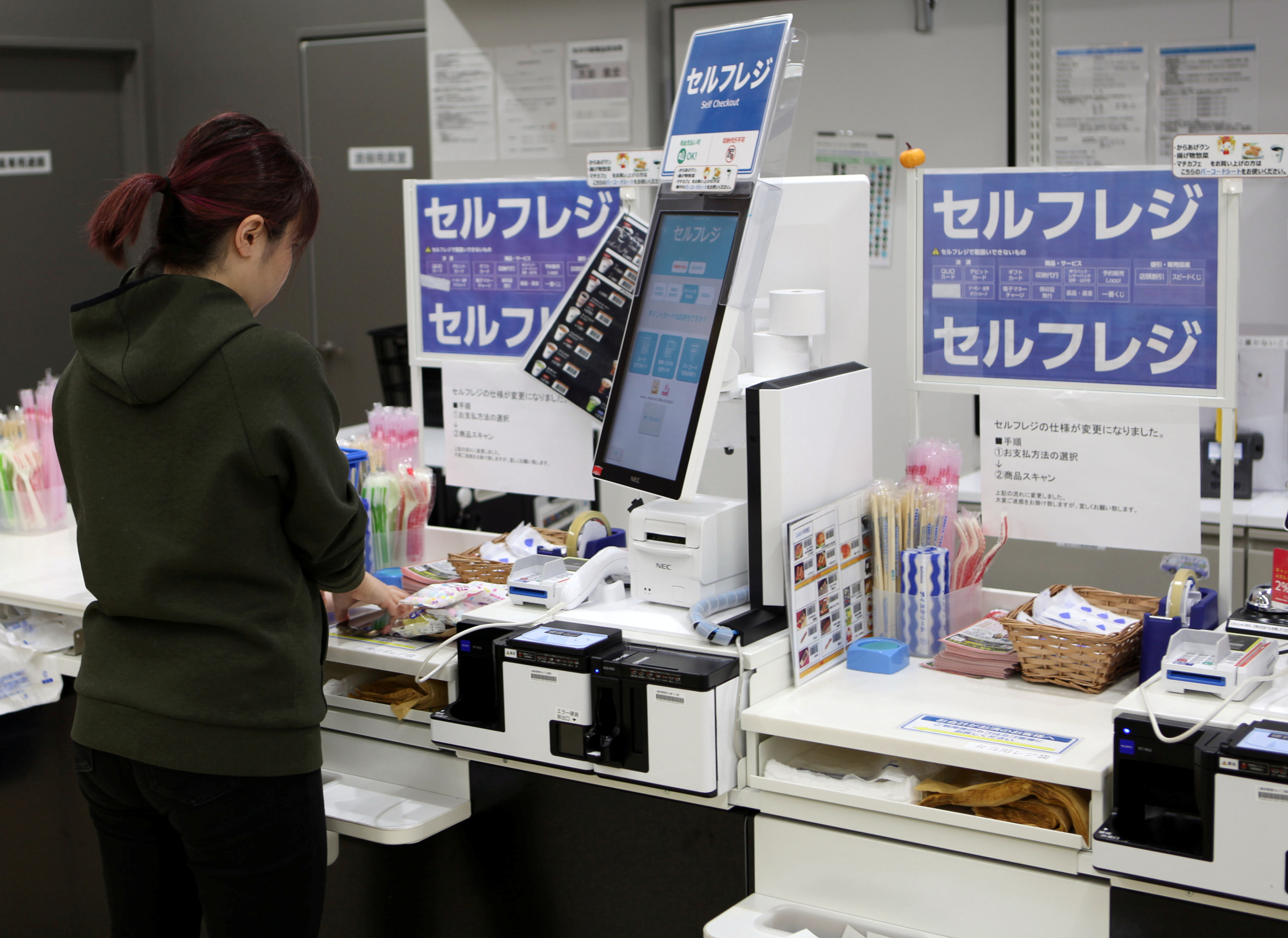 A shopper pays using her mobile phone at an unmanned cash register at a Lawson Inc. convenience store in Tokyo on Oct. 30. | REUTERS