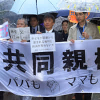 Plaintiffs seeking the joint custody of their children march outside the Tokyo District Court on Friday. | YOSHIAKI MIURA