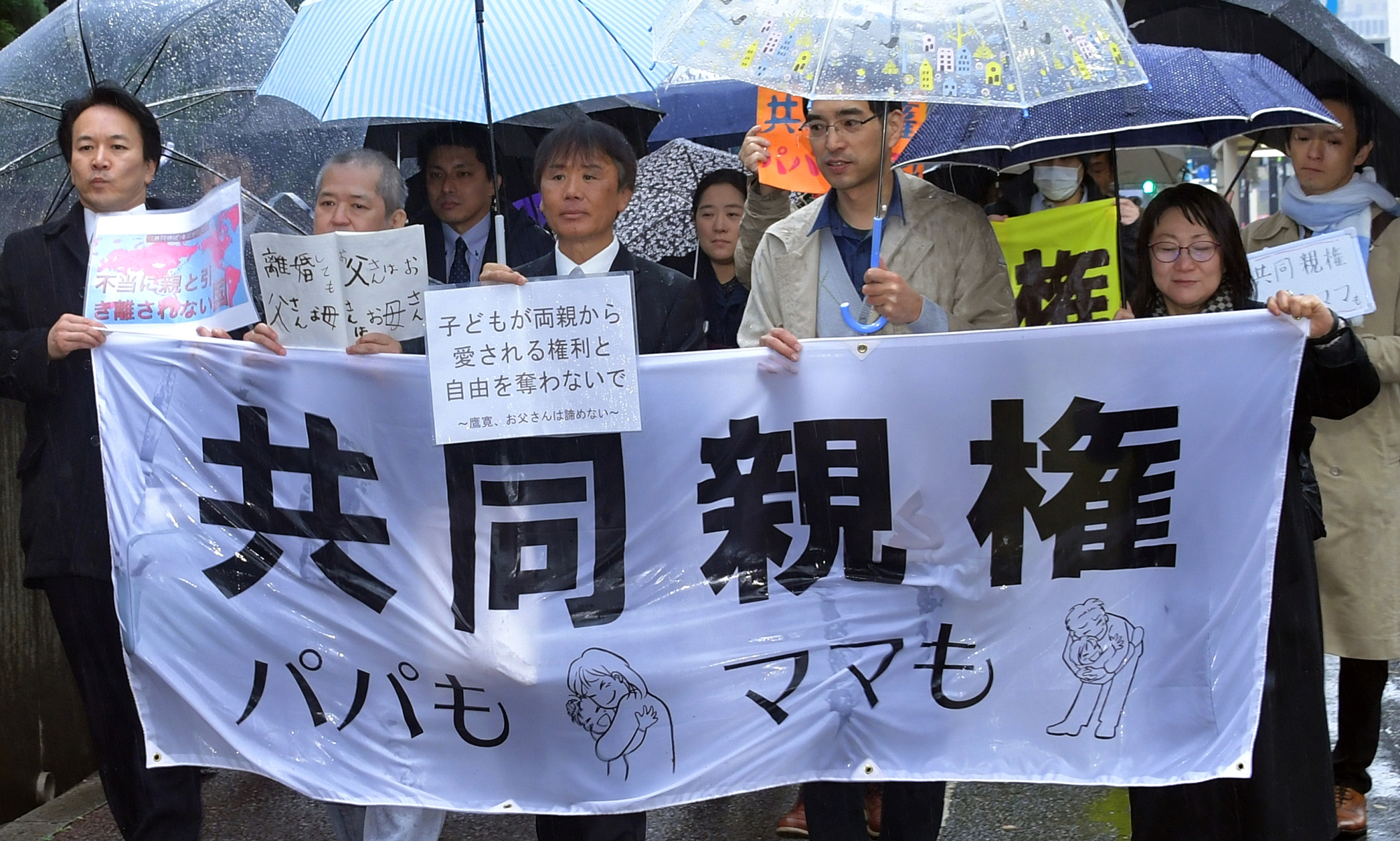 Plaintiffs seeking the joint custody of their children march outside the Tokyo District Court on Friday. | YOSHIAKI MIURA